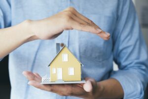 Businessman hand hold the house model saving small house.